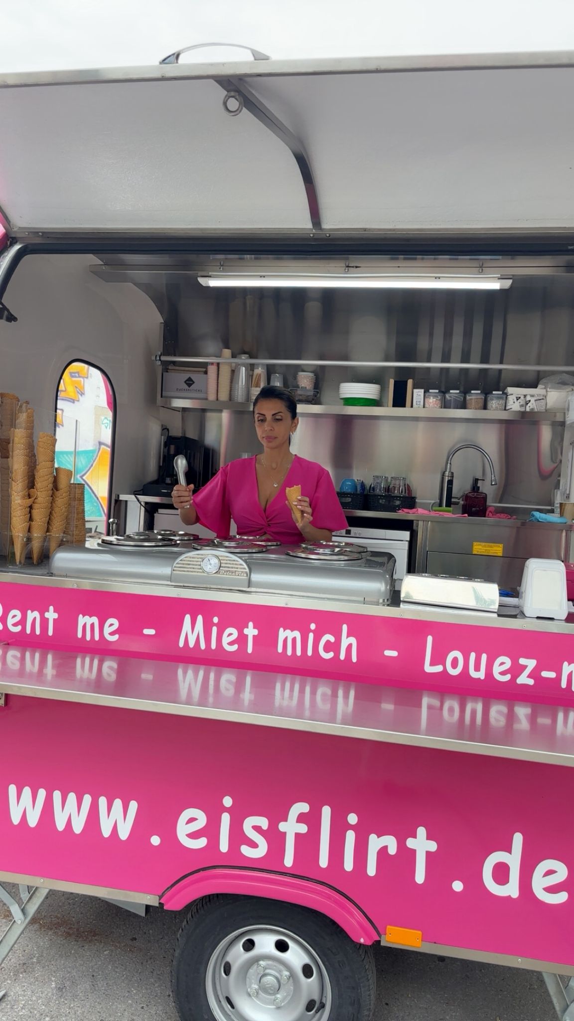 Hayriye Kalmaz im pinken Eisflirt-Eiswagen mit einer Eiswaffel in der Hand